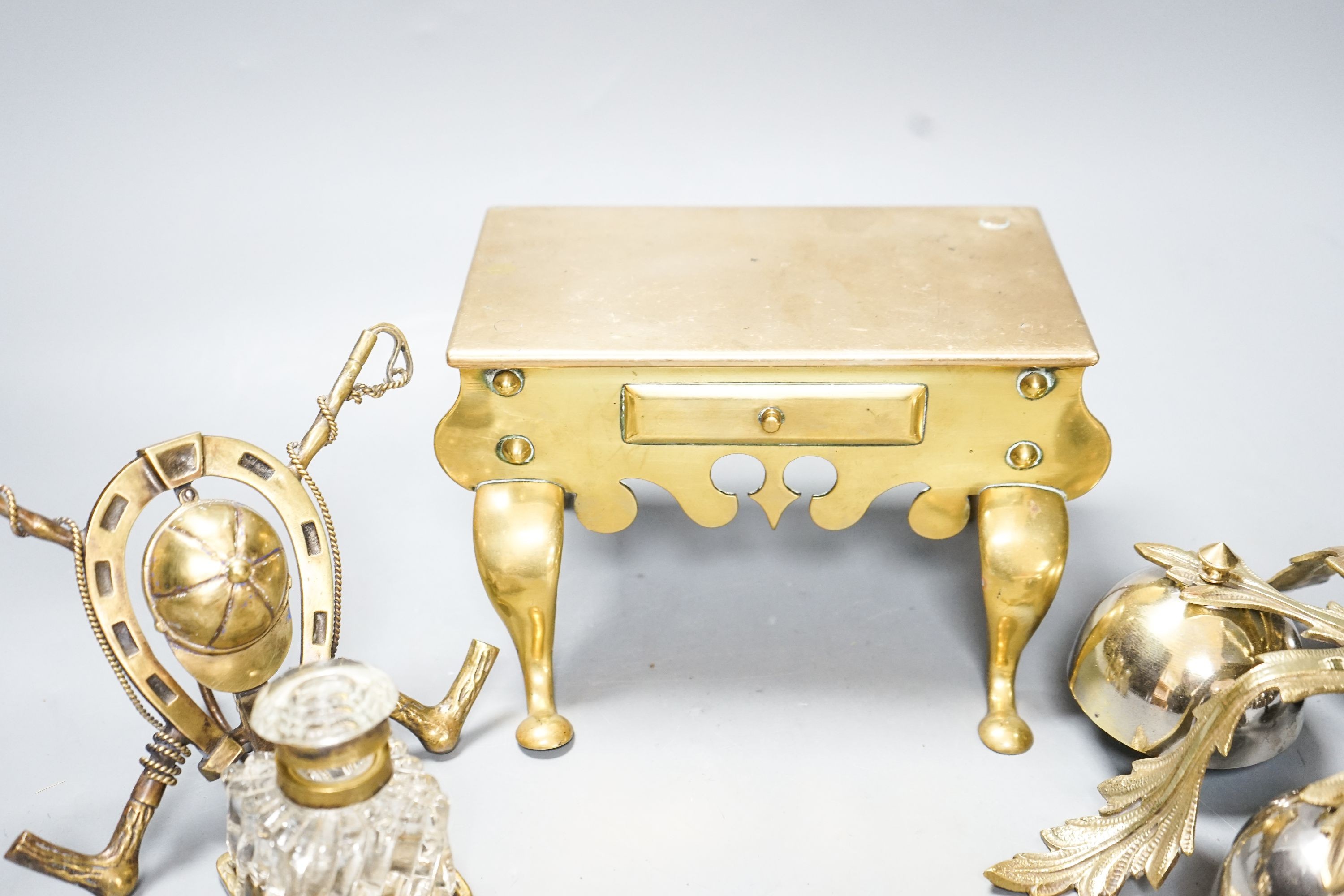 A brass Jockey-related inkwell, a miniature brass footman and brass hand bells
